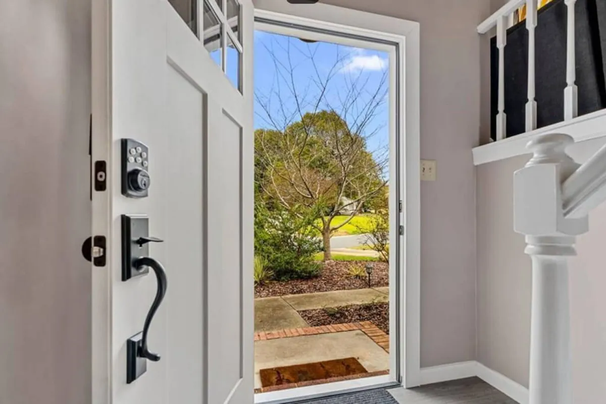 The image shows the open front door of the home, with a view of the exterior and a staircase leading inside. The inviting entryway hints at the home's welcoming nature, perfect for greeting multiple families or groups as they arrive for their stay.