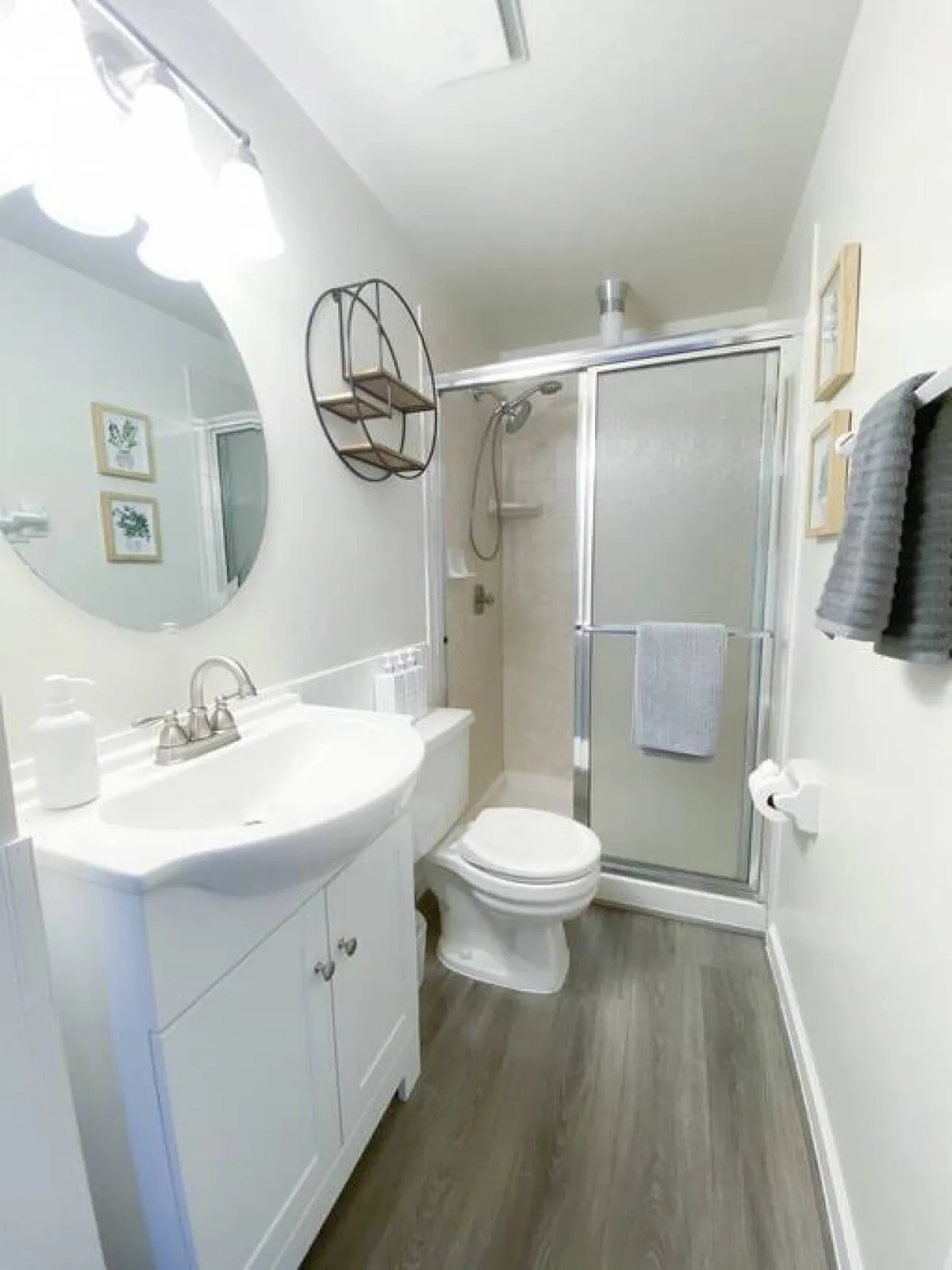 A modern bathroom featuring a sleek vanity with a sink, a spacious shower area, and tasteful decorative wall art. The setting conveys cleanliness and calm, inviting guests to enjoy moments of self-care.