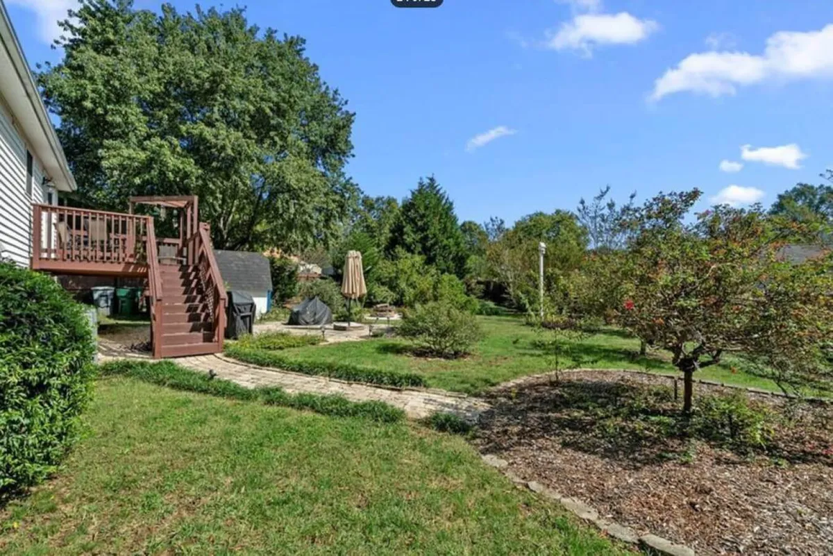 This tranquil garden shot features a lush patio area, winding garden pathways, and mature trees. Activities such as outdoor dining, gardening, and family relaxation are hinted at with the serene landscape and multiple seating options. The image is taken at sunset, enhancing the peaceful, private feel of the backyard oasis.