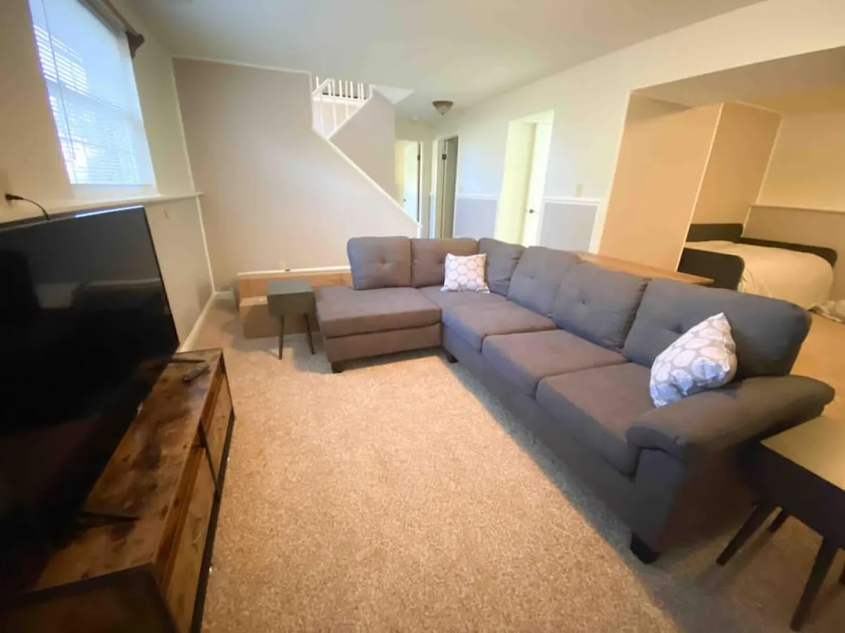 An inviting living room featuring a sectional sofa, a television set on a media stand, and a convenient side table. The space is arranged for optimal viewing and social interaction, perfect for movie nights or game evenings.
